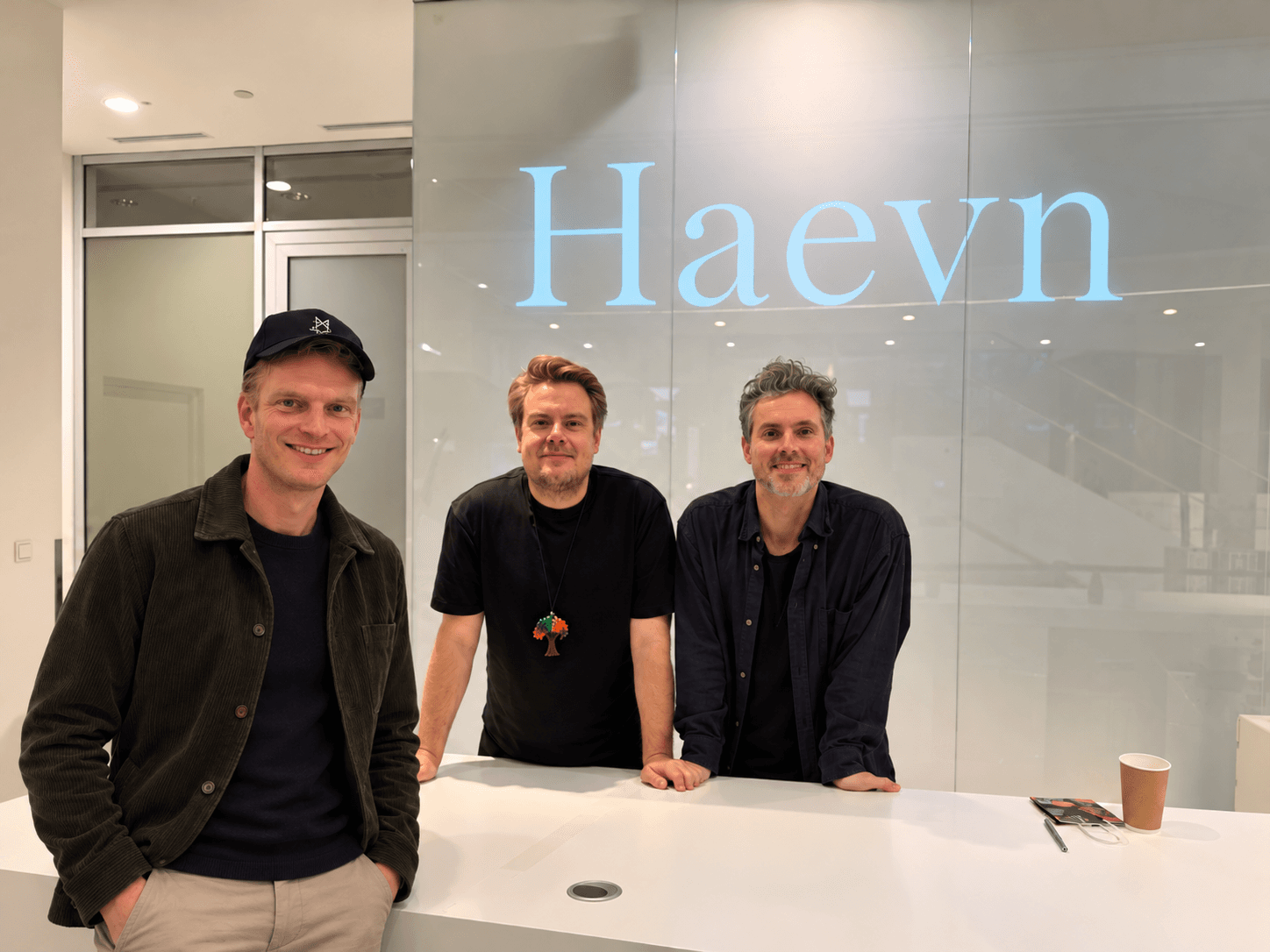 Three people in front of a glass wall bearing the name Haevn.